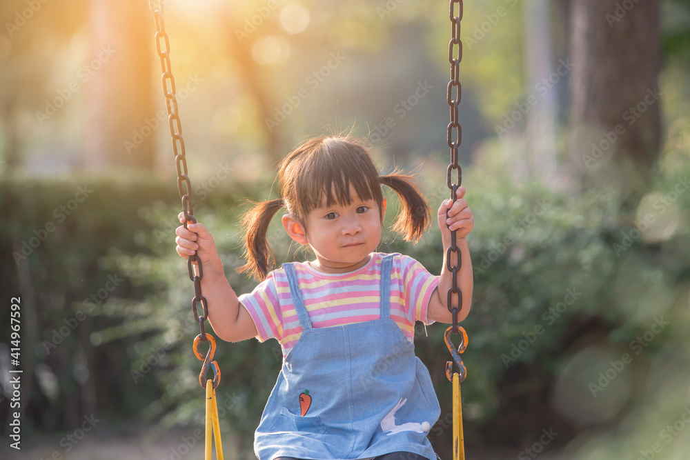 Little girl having to play swing first time in the playground , the evening Little girl having to play swing first time in the playground , the evening