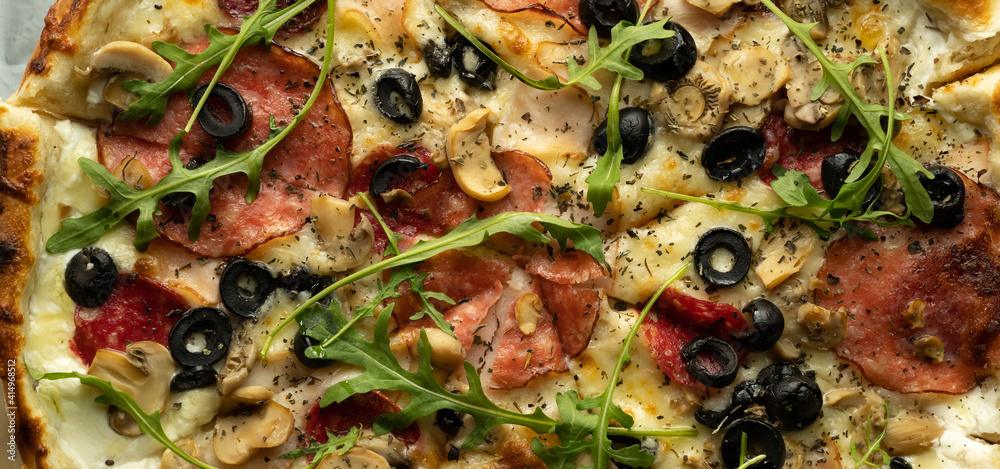Top view of pizza with olives, salami, arugula and cheese in a box. Delivery of orders from the restaurant. Top view of pizza with olives, salami, arugula and cheese in a box. Delivery of orders from the restaurant.