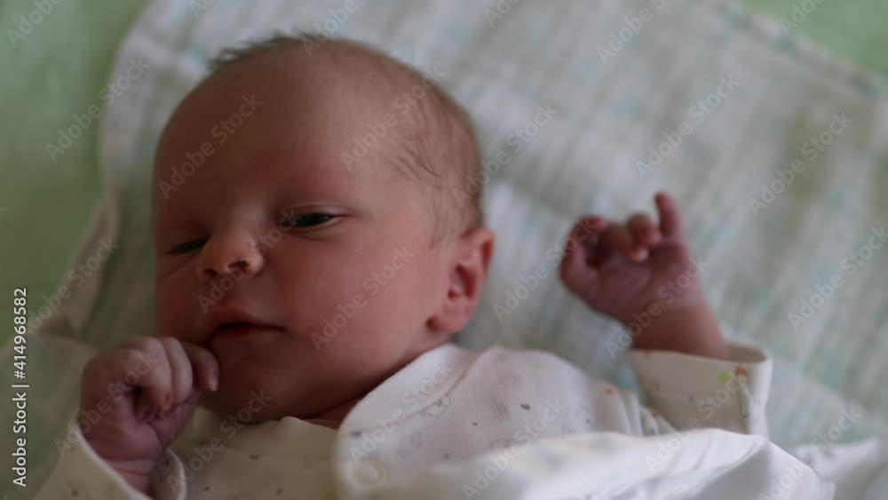 New born baby boy resting in bed exploring his hands and the world around him 