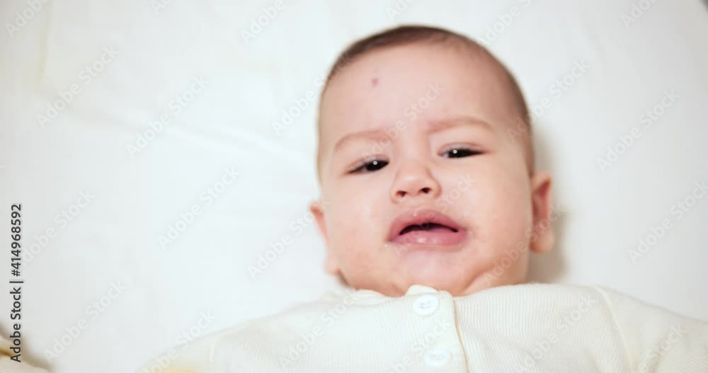 Newborn cheerful littlebaby is chewing and playing in his crib with nipple. Funny smiling looks through the railing of the crib. slow motion Newborn cheerful littlebaby is chewing and playing in his crib with nipple. Funny smiling looks through the railing of the crib. slow motion