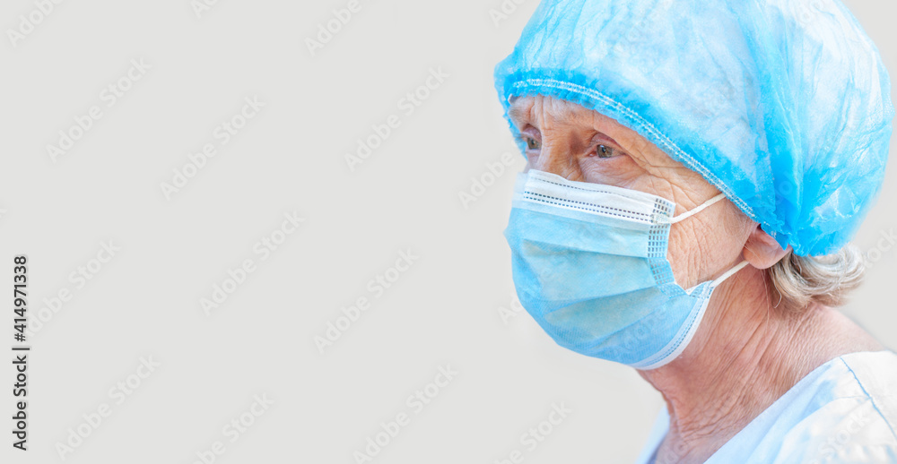 Portrait of an elderly woman doctor in medical equipment outfit. Piercing gaze a doctor clinic. Epidemic coronavirus, covid19. People health. Vaccination. Experienced elderly Physician. Blank for text Portrait of an elderly woman doctor in medical equipment outfit. Piercing gaze a doctor clinic. Epidemic coronavirus, covid19. People health. Vaccination. Experienced elderly Physician. Blank for text