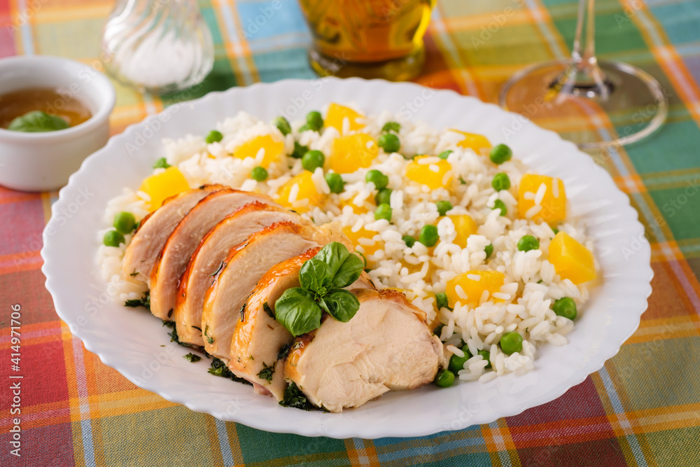 Roasted chicken breast with rice and vegetables on the white plate, horizontal orientation.