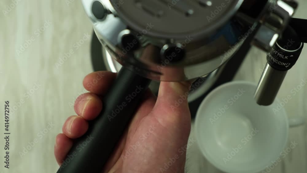 Close-up view of a male hand inserting a portafilter filled with ground coffee to make espresso coffee. The process of preparing a delicious and aromatic drink for a coffee break. Close-up view of a male hand inserting a portafilter filled with ground coffee to make espresso coffee. The process of preparing a delicious and aromatic drink for a coffee break.