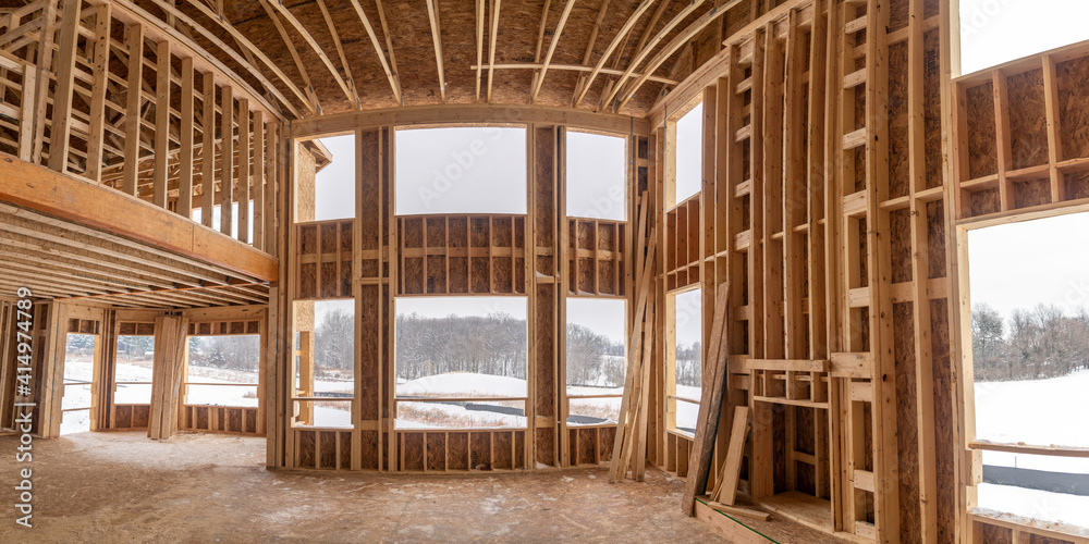 Interior view of a cathedral ceiling living room skeleton structure hole for windows, fire place at a new American real estate development construction site Interior view of a cathedral ceiling living room skeleton structure hole for windows, fire place at a new American real estate development construction site
