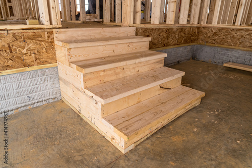 Close up view of wooden five step stair case leading up from a garage into a house at a new construction American real estate development