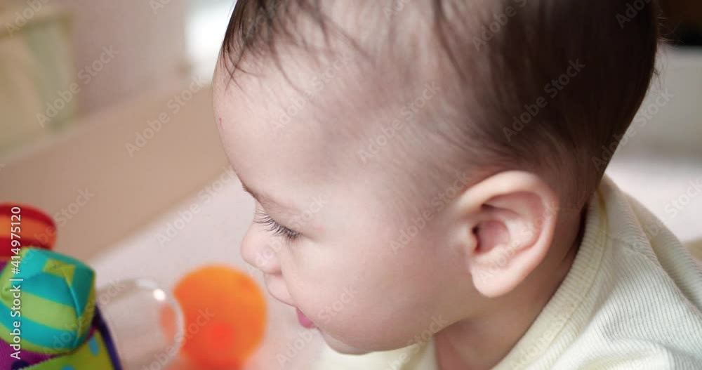 infant, childhood concept - close-up of smiling happy Baby plays with a teether. Teeth cutting. First teeth. Joy toothless 7 months baby bite, gnaws teether toy. slow motion infant, childhood concept - close-up of smiling happy Baby plays with a teether. Teeth cutting. First teeth. Joy toothless 7 months baby bite, gnaws teether toy. slow motion