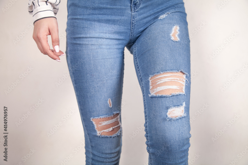 Young woman in modern torn jeans at home.