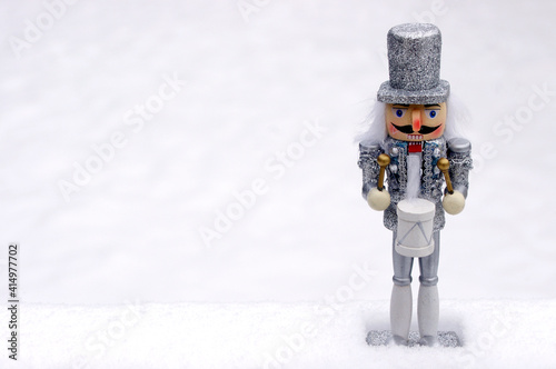 silver toy nutcracker in white snow with copy space