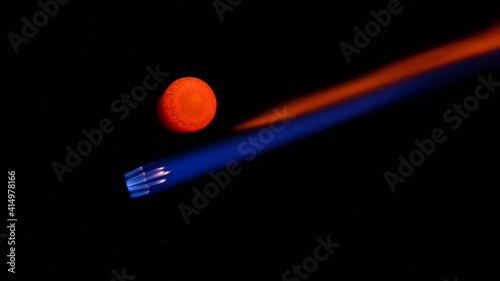 A Lampworkers blue and red torch flame as he pulls the formed molten glass out of it 