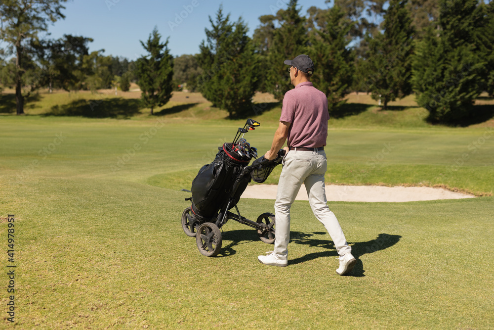 Caucasian senior man walking across golf course holding golf bags Caucasian senior man walking across golf course holding golf bags