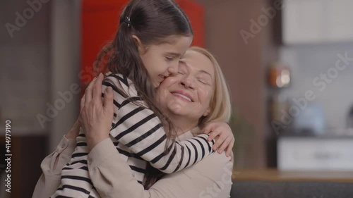 Beautiful little girl who came to see her grandmother. The girl runs and hugs her grandmother. Portrait of love for grandchildren.Slow motion video.