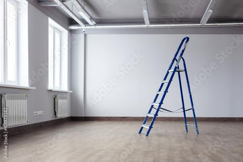 Fotografi A dirty blue metal stepladder against a newly painted gray wall, windows in a new building