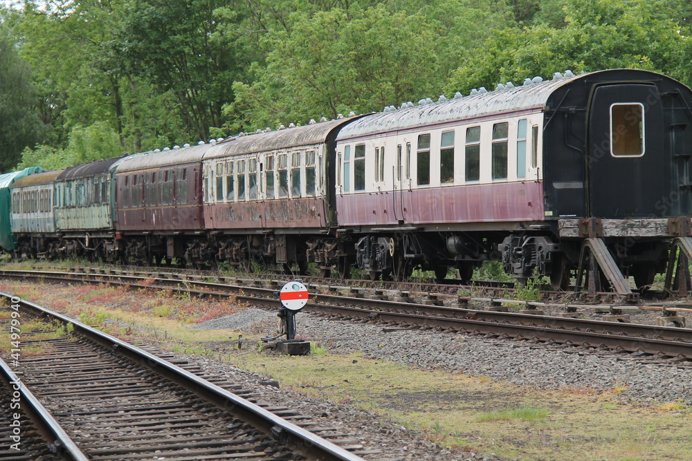 Obraz premium A Row of Vintage Railway Carriages Awaiting Restoration.