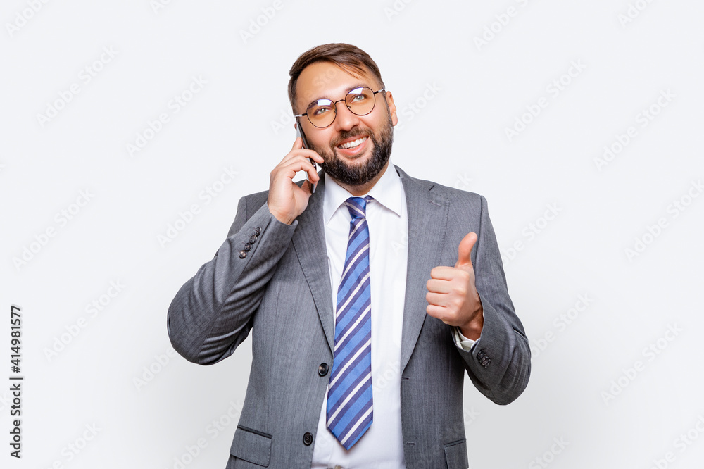 businessman wearing glasses wearing business gray suit smiling and talking on cellphone isolated. light background. businessman wearing glasses wearing business gray suit smiling and talking on cellphone isolated. light background.