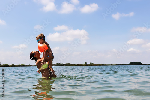 Carefree mother and son having fun in the water in summer day, © LumineImages