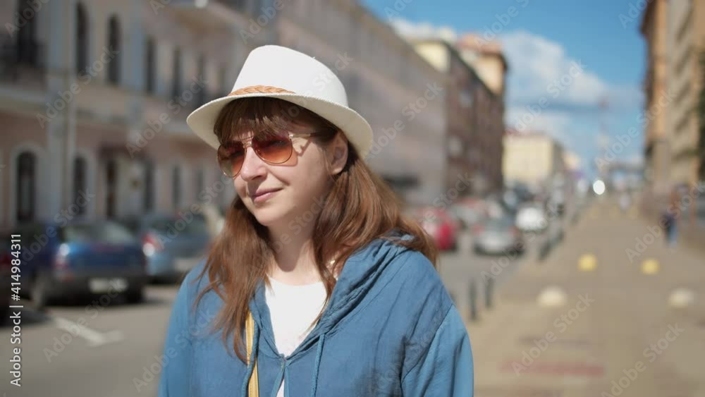 traveler woman in hat walking through the city and looking around, smiling traveler woman in hat walking through the city and looking around, smiling