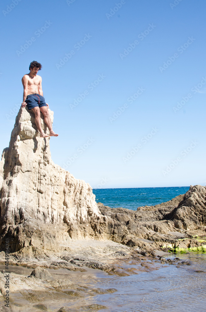 young man on top of a stone on the coast