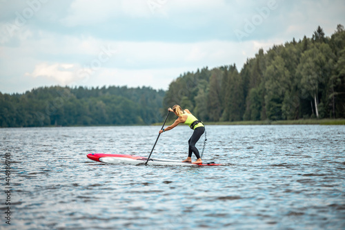 Strong and fit woman paddle with SUP stand up paddle board in lake. SUP competition, race concept