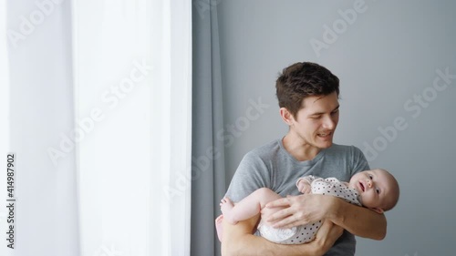 Young happy father sings a lullaby to the child. The newborn does not sleep