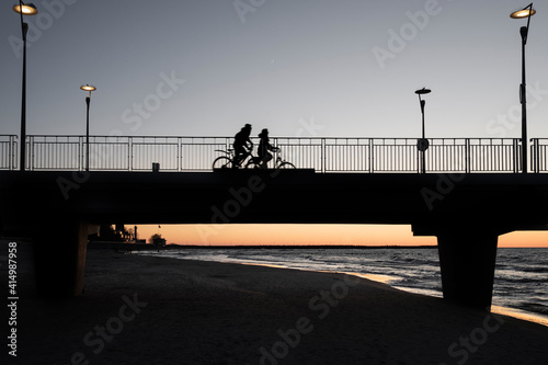 Sylwetka pary rowerzystów na molo w Kołobrzegu o zachodzie słońca