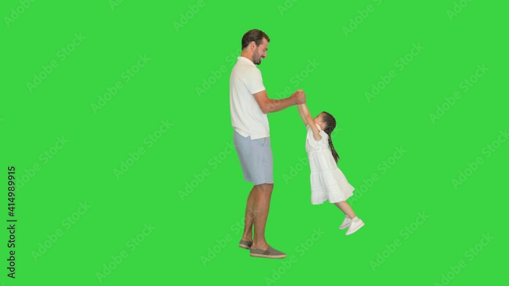 Happy father holding his daughter's hands and spinning around letting her fly on a Green Screen, Chroma Key. Happy father holding his daughter's hands and spinning around letting her fly on a Green Screen, Chroma Key.