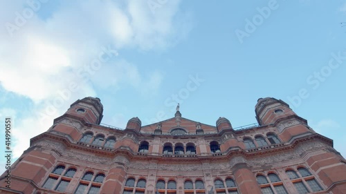 Low angle shot looking up at Palace Theatre London with blue sky and white clouds and birds flying across photo