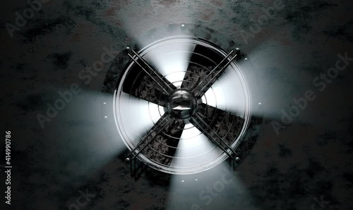 A huge old, rusty fan in the ventilation system rotates slowly and rays of light pass through it