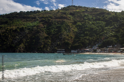 Town on the edge of the mountain with its turquoise sea of strong waves in front in Chichiriviche de la Costa, Vargas Venezuela photo