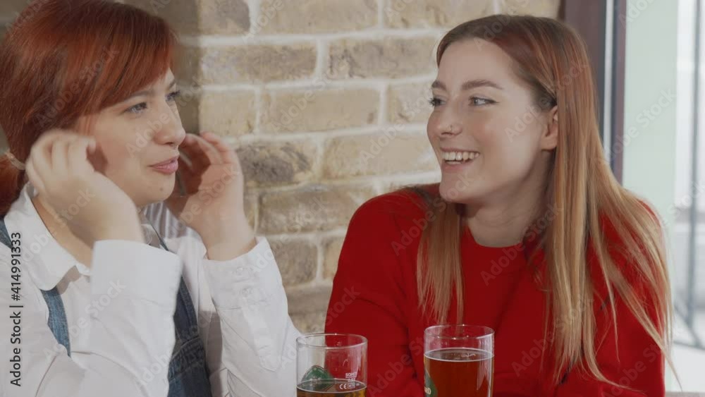 Female friends chatting at the beer pub. Two young women having fun together, drinking beer and talking at the bar. Communication, weekend, leisure concept Female friends chatting at the beer pub. Two young women having fun together, drinking beer and talking at the bar. Communication, weekend, leisure concept