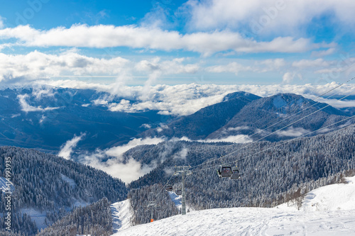 SOCHI, RUSSIA - JANUARY 30, 2021: Beautiful snow landscape of snowy trees and ski lift of Roza Khutor ski resort. South part of mountains with sunny weather.