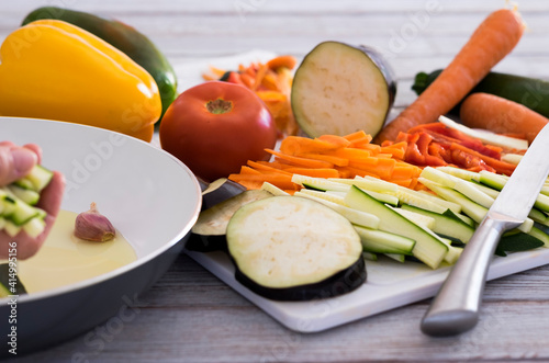 Wooden table with a mix of sliced vegetables, carrots, zucchini, eggplant and peppers ready to be cooked - healthy eating vegetarian vegan concept photo