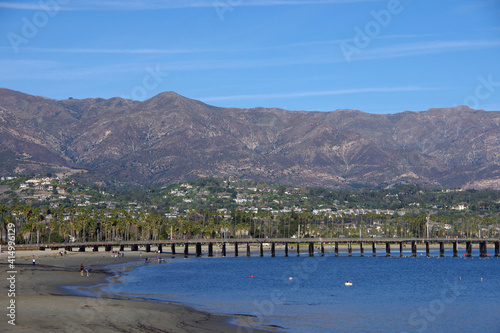 A panoramic view from the west side of the Santa Barbara bay with the pier and the Santa Ynez mountains in the back and blue sky above on a nice southern California winter day