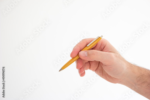 Yellow vintage plastic ball pen held in hand by Caucasian male hand making gesture studio shot isolated on white