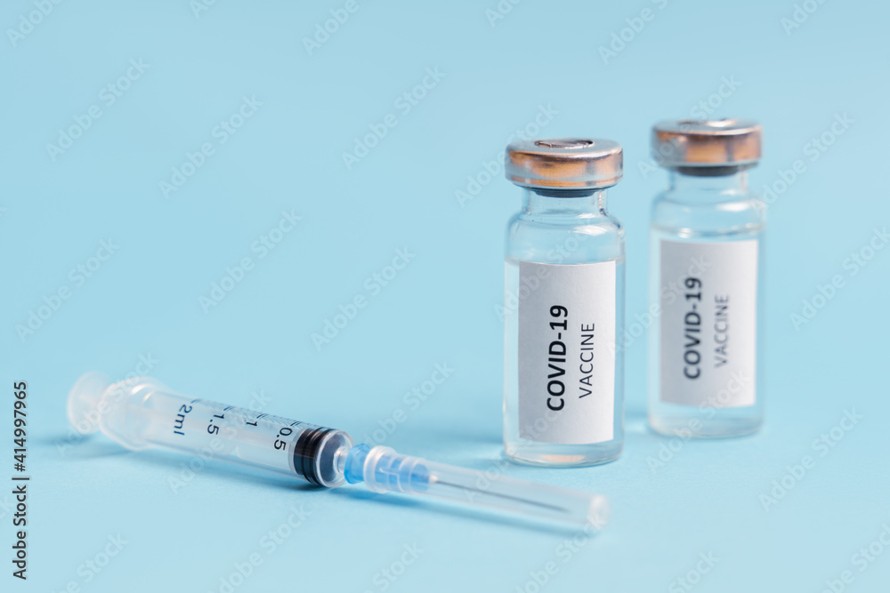 Vaccine and syringe injection against blue background. Coronavirus vaccine. COVID-19 immunization. Vaccine and syringe injection against blue background. Coronavirus vaccine. COVID-19 immunization.