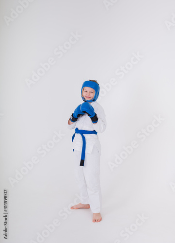 boy in a white kimono, sports helmet, boxing gloves stands in a pose on a white background with a place for text