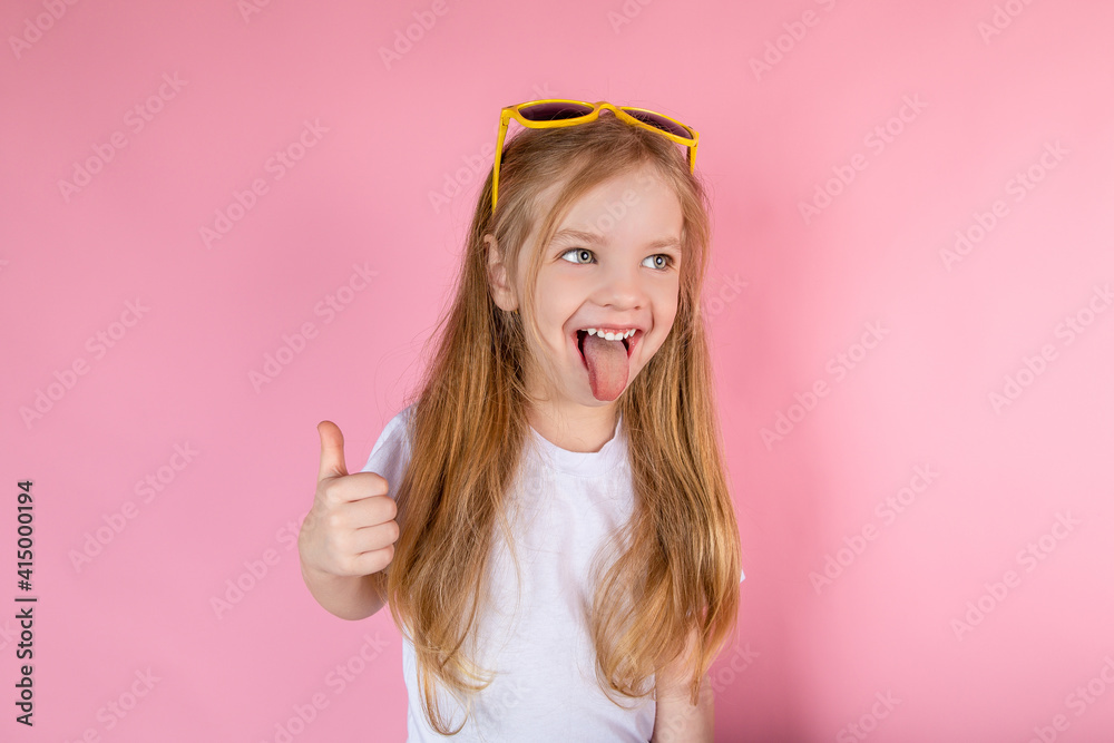 Child in sunglasses showing tongue showing cool on pink background Child in sunglasses showing tongue showing cool on pink background