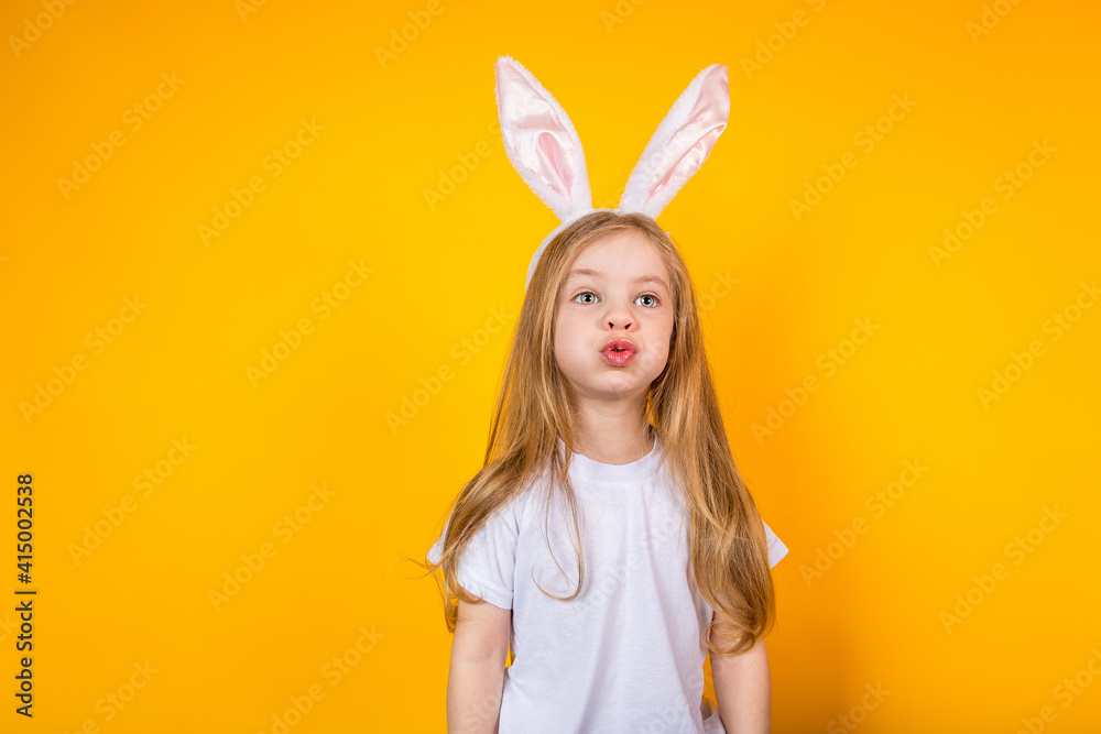 Baby girl in a white T shirt wearing bunny ears on a yellow background Baby girl in a white T shirt wearing bunny ears on a yellow background
