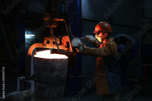Obraz na plátne A steelmaker pours pig iron from a blast furnace, sparks and splashes of hot metal fly