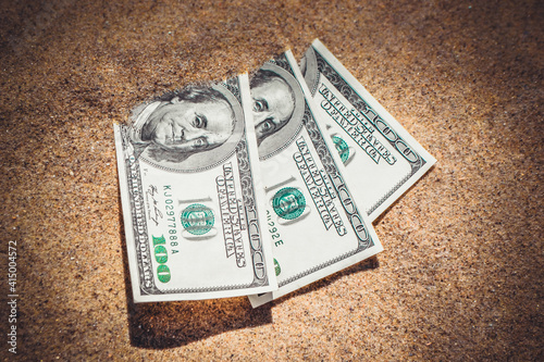 Money dolars half covered with sand lie on beach close-up. photo