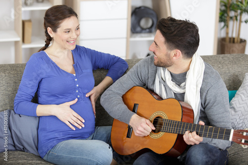 husband playing the guitar for his beautiful pregnant wife