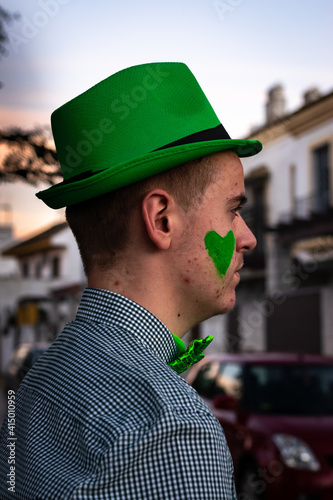 profile boy wearing a green cap and bow tie at sunset on St. Patrick's Day