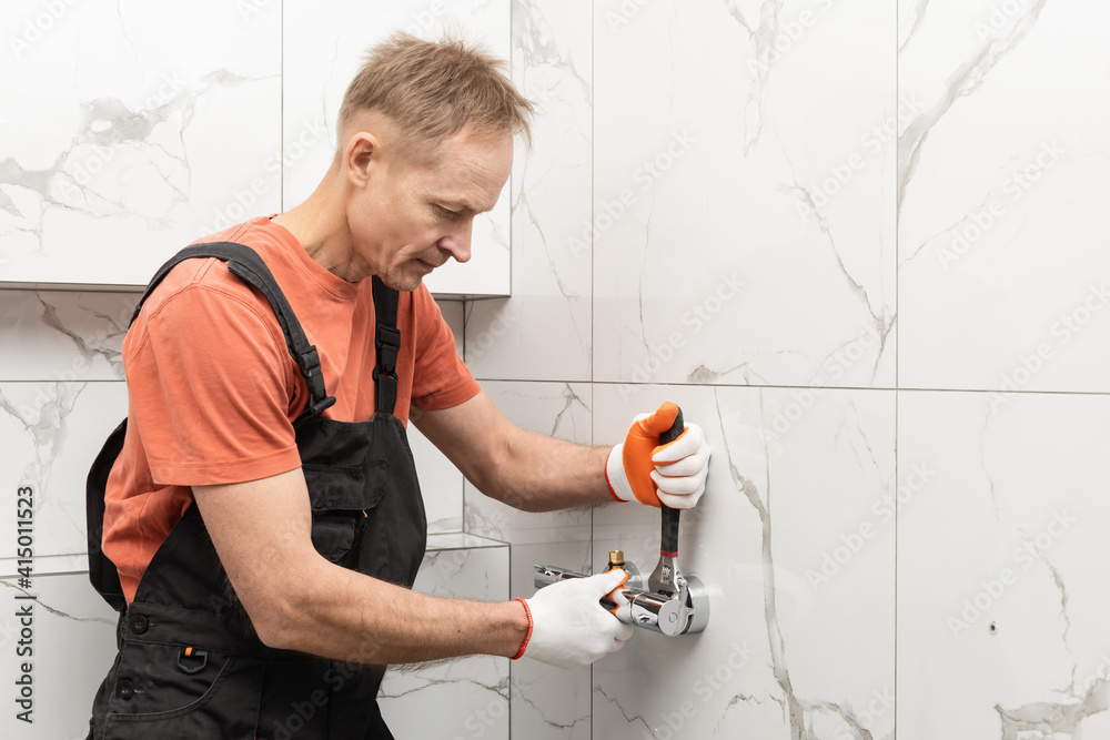 The plumber is installing a shower faucet with an adjustable wrench. The plumber is installing a shower faucet with an adjustable wrench.