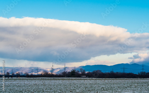 Big cloud like in movie "Independence day" in blue sky over winter landscape © Gabdulvachit