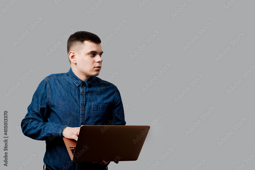 Handsome man with laptop on the gray background. Business man working online at home. Handsome man with laptop on the gray background. Business man working online at home.