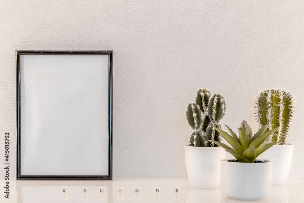 Fototapeta premium Modèle de cadre photo noir avec espace vide pour logos, inscription publicitaire. Cadre en mode portrait sur un espace de travail avec des plantes vertes. Message 