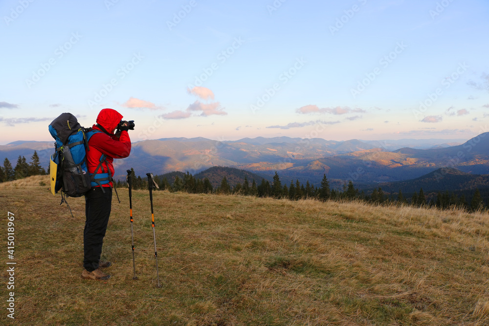 hiker in the mountains photographing the sunset