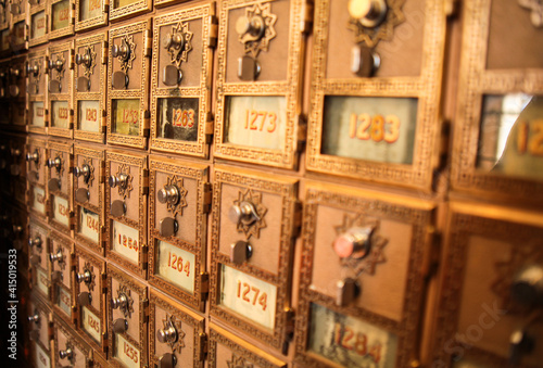 Grid of ornate gold bronze colored mailboxes in a unique perspective, typically seen at a post office