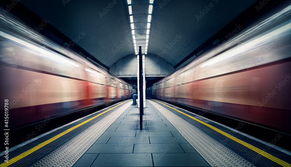 Two trains in motion and a seated commuter at London Tube Station, Clapham Common, Clapham, London Two trains in motion and a seated commuter at London Tube Station, Clapham Common, Clapham, London