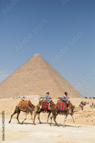 Local men riding camels, Khufu Pyramid in the background, Great Pyramids of Giza, Giza, Egypt photo