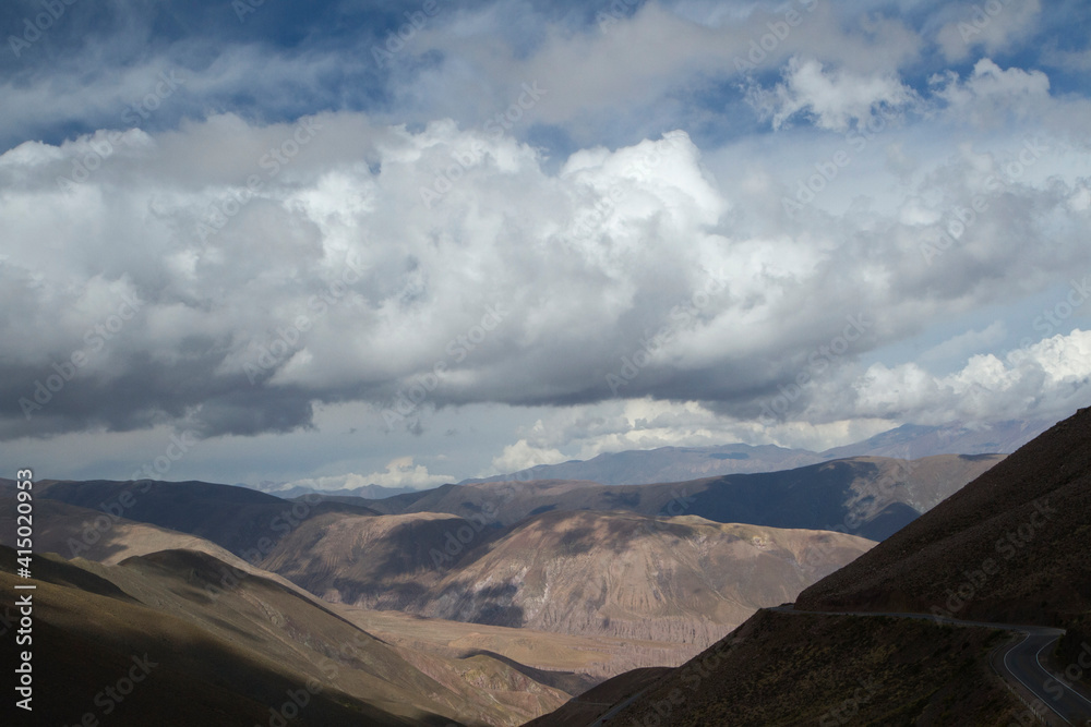 The Andes mountain range under a magical sky. Aerial view of the desert road across the rocky hills.